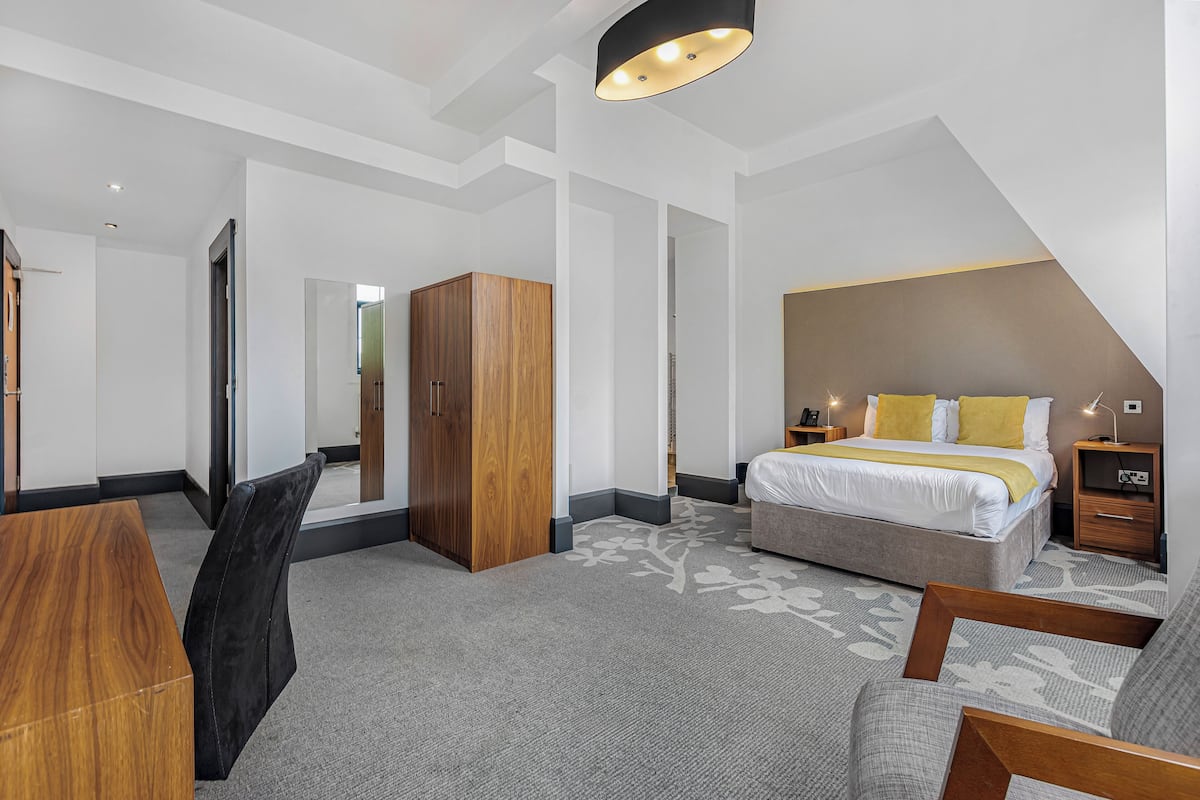 Una habitación de hotel moderna con una cama grande, un escritorio y un armario.