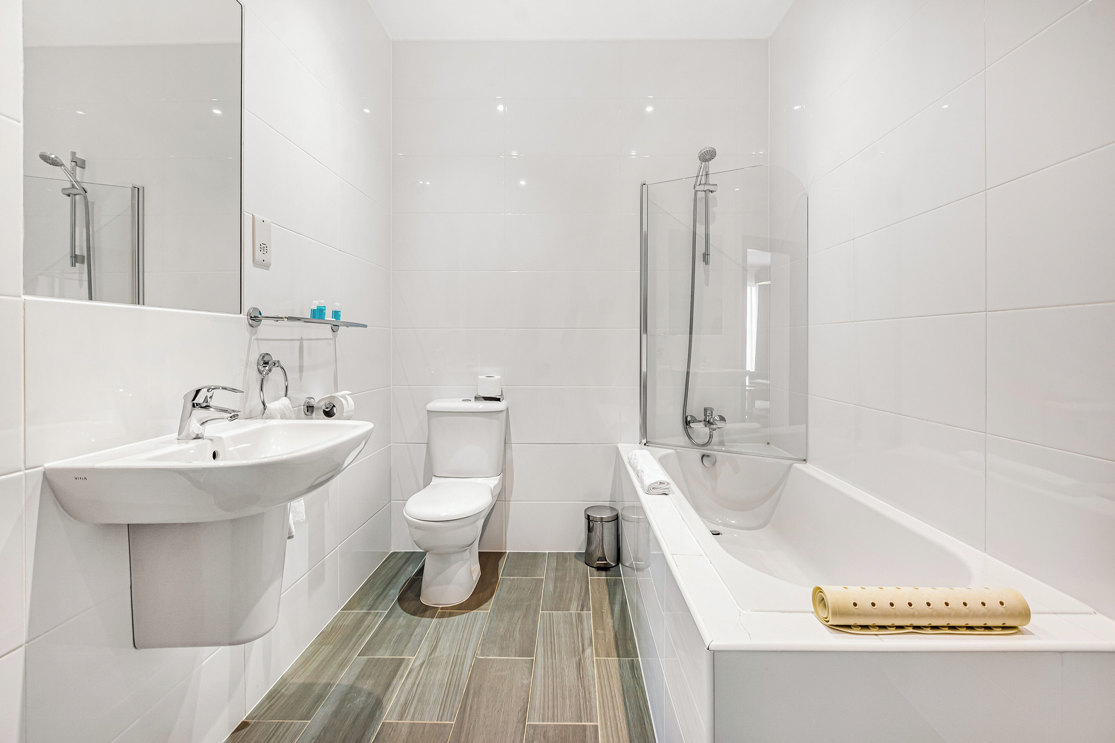 A modern bathroom with a sink, toilet, and bathtub.