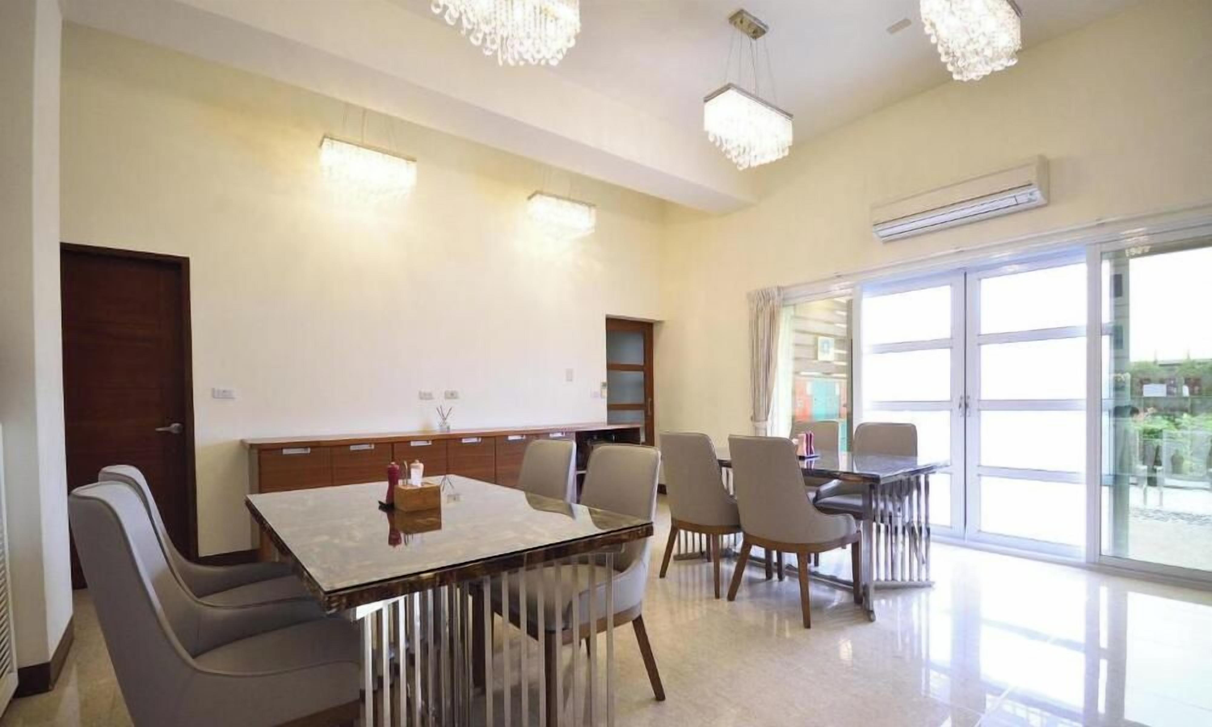 A dining area with a table and chairs, a chandelier, and a large window with a view.