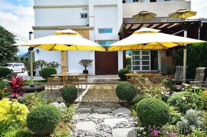 A patio area with outdoor seating, yellow umbrellas, and a stone pathway leading to a building entrance.