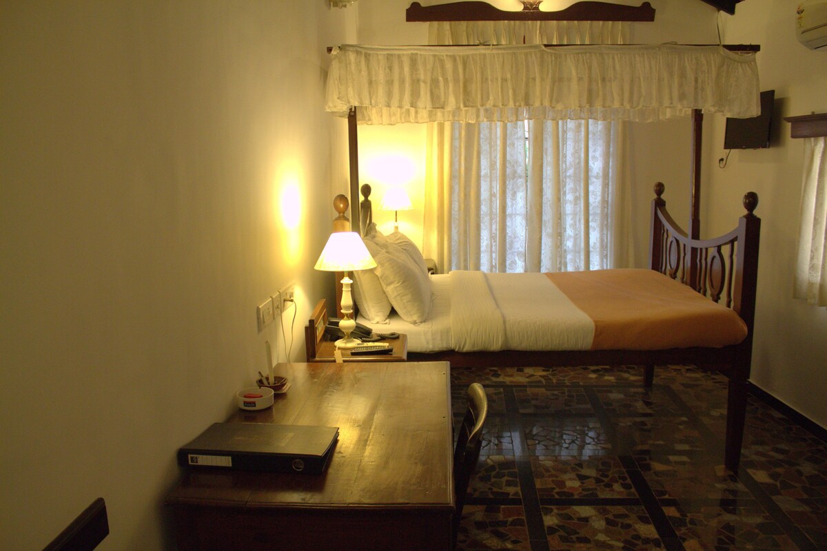 Quarto com cama, mesa de cabeceira, abajur e uma cadeira.