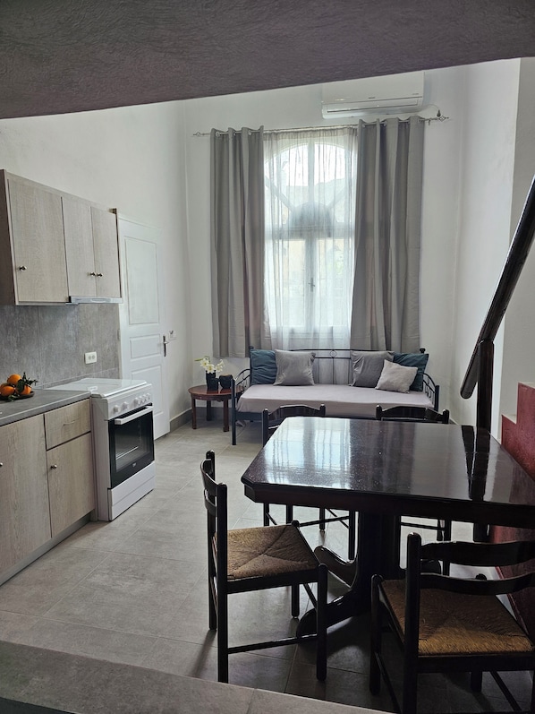 Un espacio habitable compacto con kitchenette, comedor y sofá cama.
