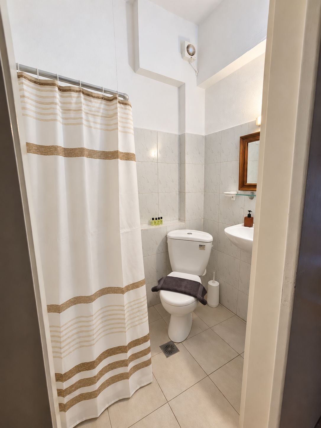 Een badkamer met toilet, wastafel en douchegordijn.