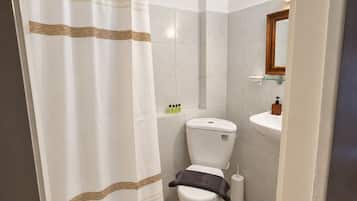 Een badkamer met toilet, wastafel en douchegordijn.
