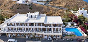 A multi-story hotel with a rooftop pool and outdoor seating. - Porto Castello (Santorini)