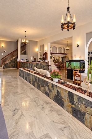 A spacious living area with a stone accent wall, a large fish tank, and a staircase leading to an upper level. - Porto Castello (Santorini)
