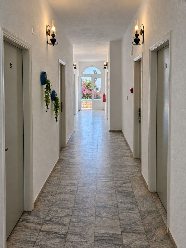 A hallway with doors numbered 8 and 9, leading to a balcony with a view.