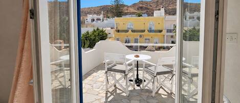 A balcony with a table and chairs, a view of buildings, and a clear sky.