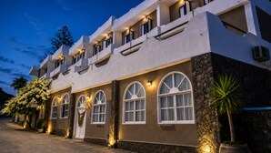 A multi-story hotel with arched windows and a stone facade. - Porto Castello (Santorini)