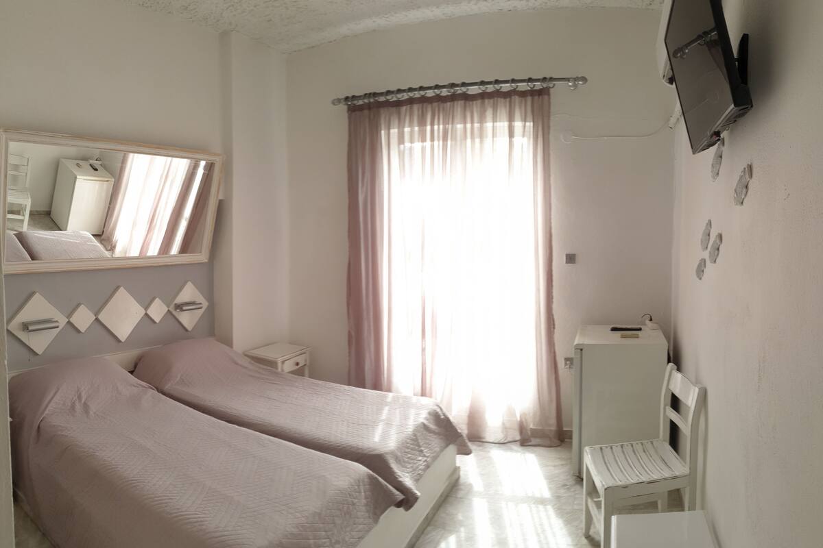 A bedroom with two beds, a TV, a desk, and a chair.
