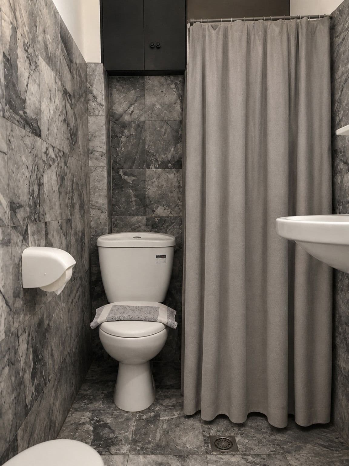 A bathroom with a toilet, a shower curtain, and a sink.
