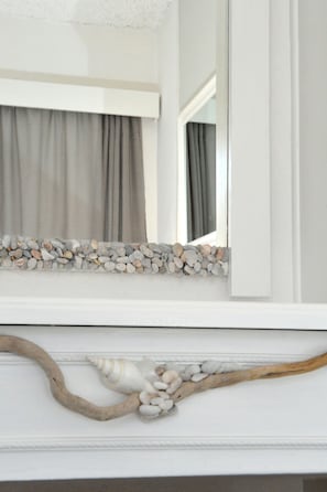 Un aparador blanco con una composición decorativa de piedras y conchas.