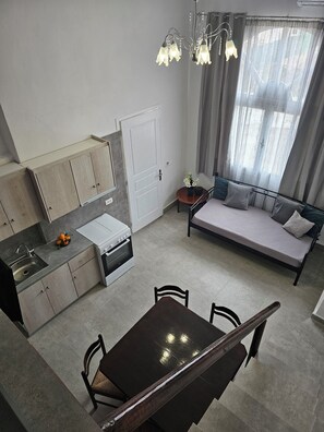Una cocina moderna con zona de comedor, sofá cama y mesa con sillas.
