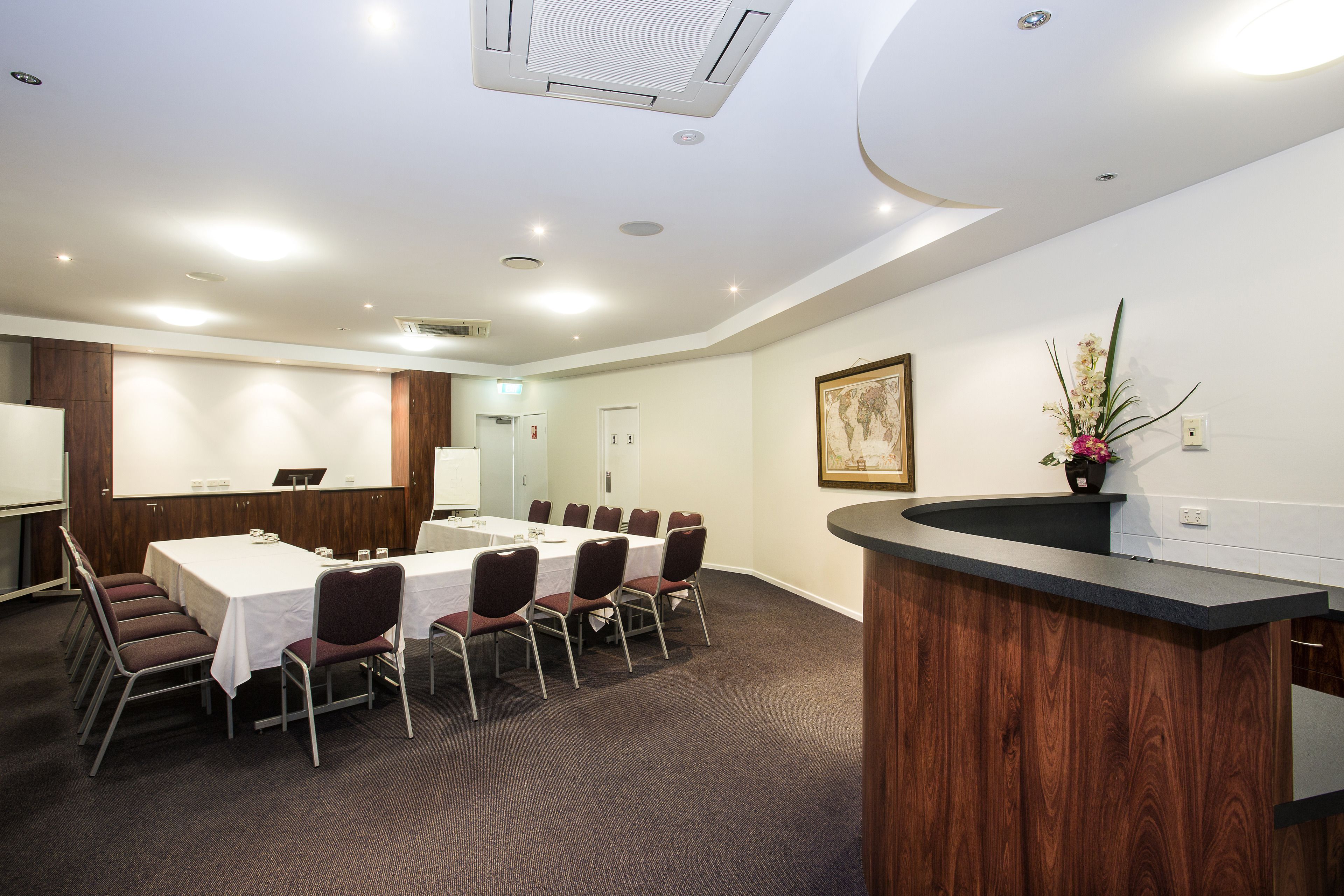 A conference room with a long table, chairs, a whiteboard, and a wooden reception desk.