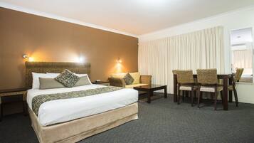 Een hotelkamer met een groot bed, een klein tafeltje en vier rieten stoelen.