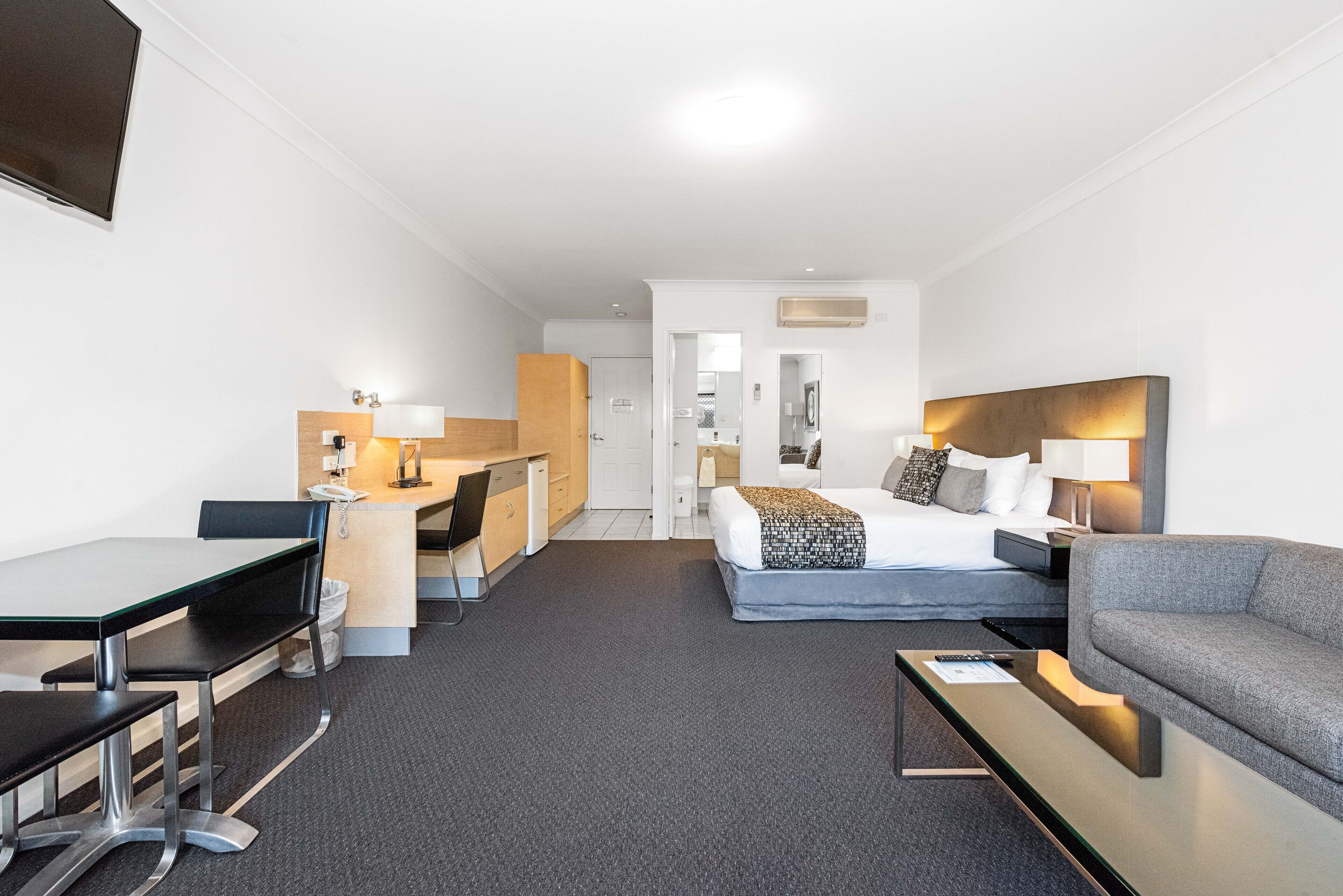 Habitación de hotel con cama, sofá, escritorio y silla.