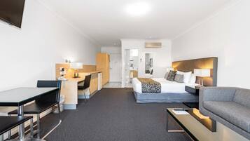 Habitación de hotel con cama, sofá, escritorio y silla.