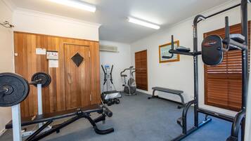 Een sportschool met een bankdrukrek, een squatrek, een bank en een optrekstang.