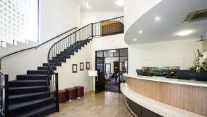 Un hall d’hôtel avec un escalier, un comptoir d’accueil et une vue sur l’intérieur.