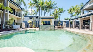 Een buitenzwembad, ligstoelen bij het zwembad