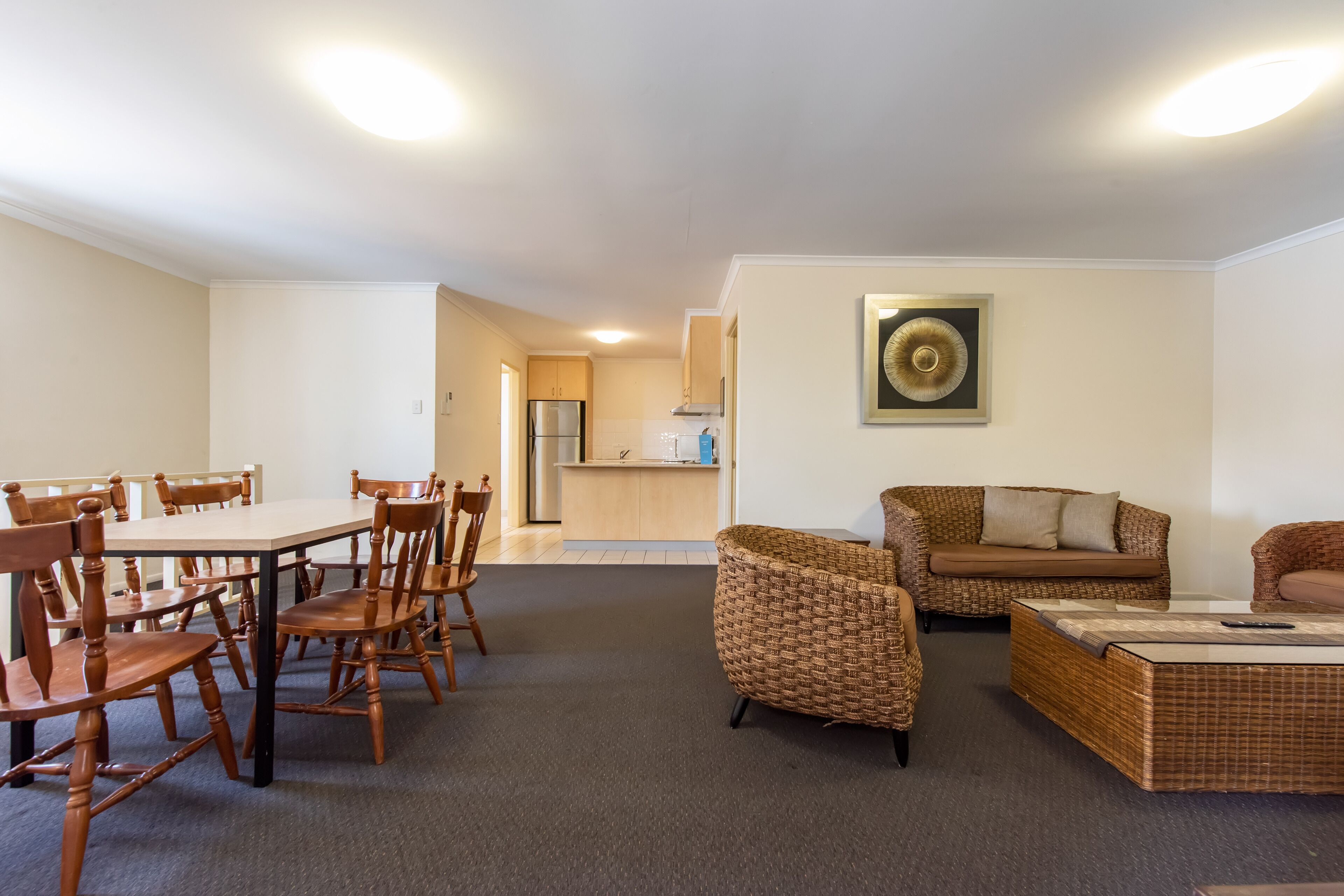 A spacious living area with a dining table, chairs, a sofa, and a kitchen in the background.