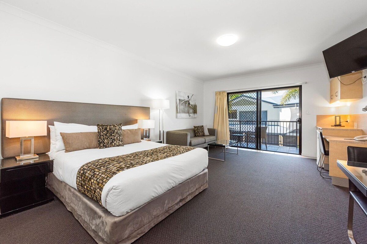 Une chambre d’hôtel avec un grand lit, un bureau, une chaise, une télévision et un balcon avec vue.