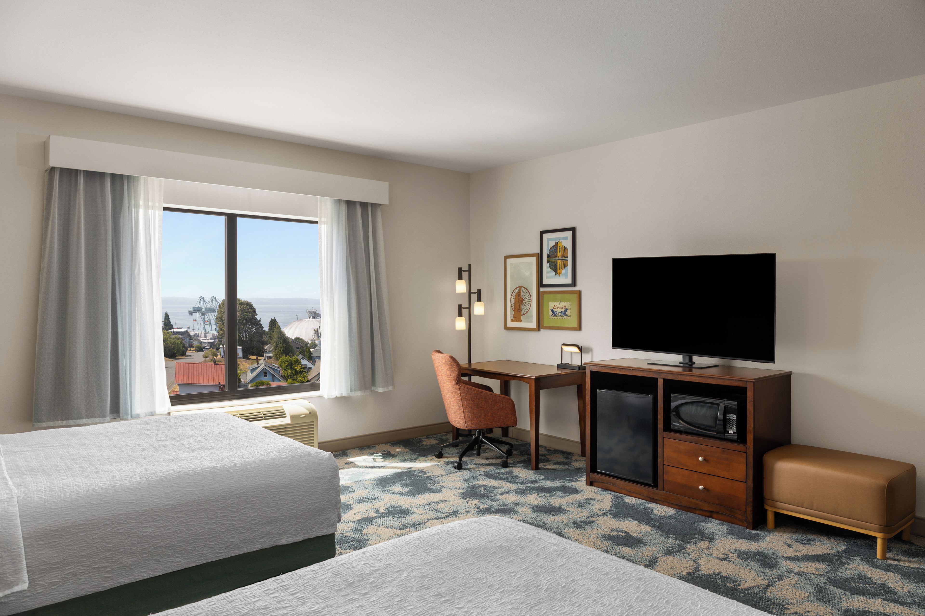 Une chambre d’hôtel avec deux lits, un bureau, une télévision et une vue sur la ville.