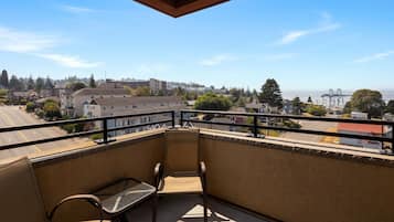 A balcony with a view of a cityscape, a bench, and a railing.