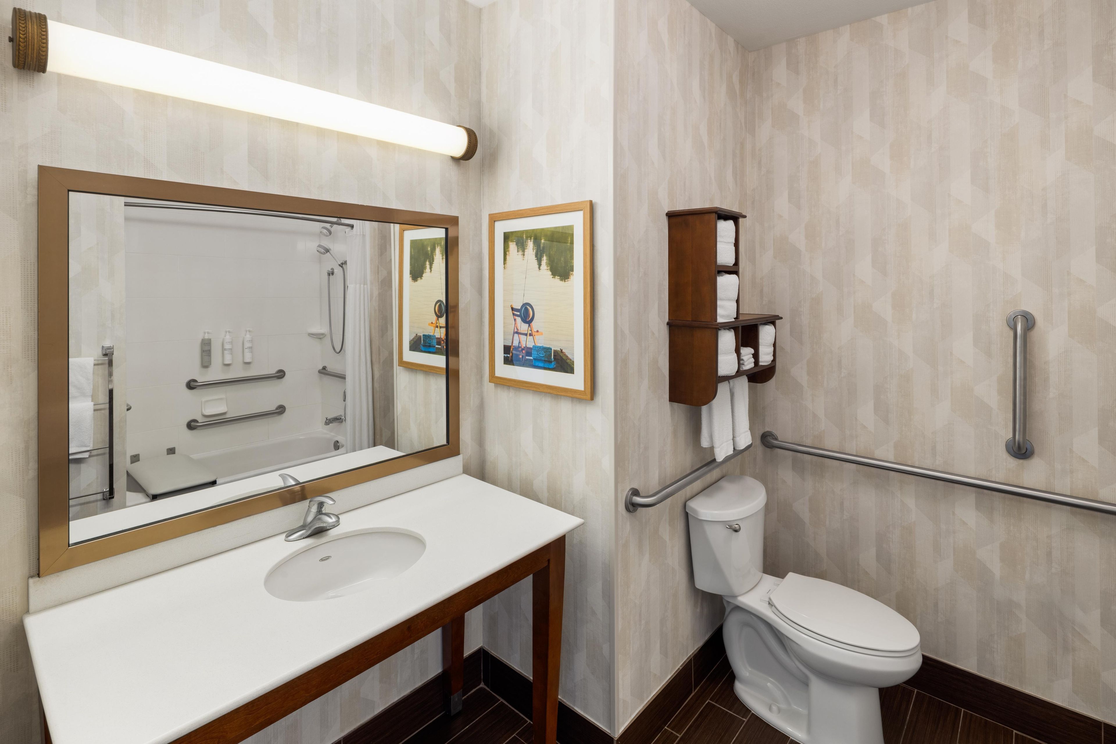 A modern bathroom with a white sink, a large mirror, a toilet, and a shower.