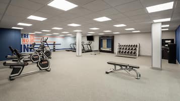 A gym with treadmills, elliptical machines, a bench, and a wall with motivational text.