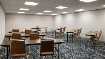 A conference room with tables and chairs, carpeted floor, and ceiling lights.