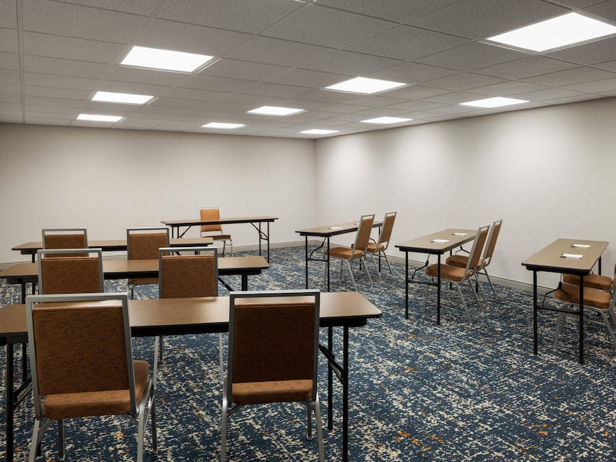 A conference room with tables and chairs, carpeted floor, and ceiling lights.