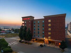 A Hampton Inn hotel with a brick facade, multiple floors, and a parking area.