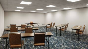 A conference room with tables and chairs, carpeted floor, and ceiling lights.
