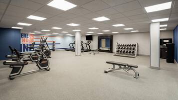 A gym with treadmills, elliptical machines, a bench, and a wall with motivational text.