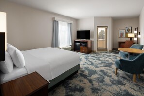 A hotel room with a large bed, a desk, a television, a seating area with chairs, and a window with curtains. - Hampton Inn Seattle/Everett (Everett)