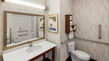A modern bathroom with a white sink, a large mirror, a toilet, and a shower.