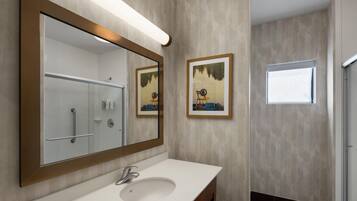 A bathroom with a large mirror, a sink, and two framed pictures on the wall.