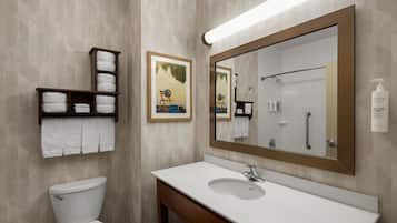 A bathroom with a toilet, a sink, a large mirror, and shelves with towels.