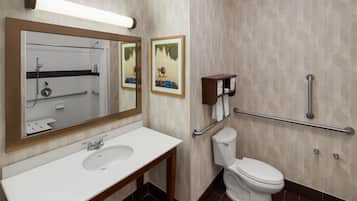 A modern bathroom with a white sink, a toilet, a shower, and two framed pictures on the wall.