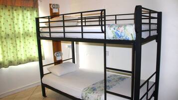 Ein Stockbett mit zwei Etagen, ein Fenster mit Vorhang und ein Wandventilator.