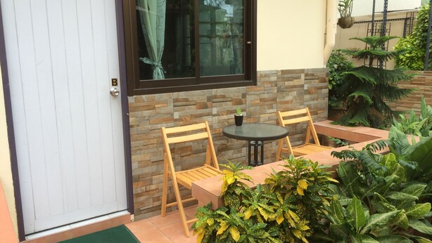 Un patio con una mesa, sillas, una puerta y una ventana con cortinas.