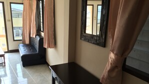 Una habitación con un sofá negro, una mesa de madera y un espejo en la pared.