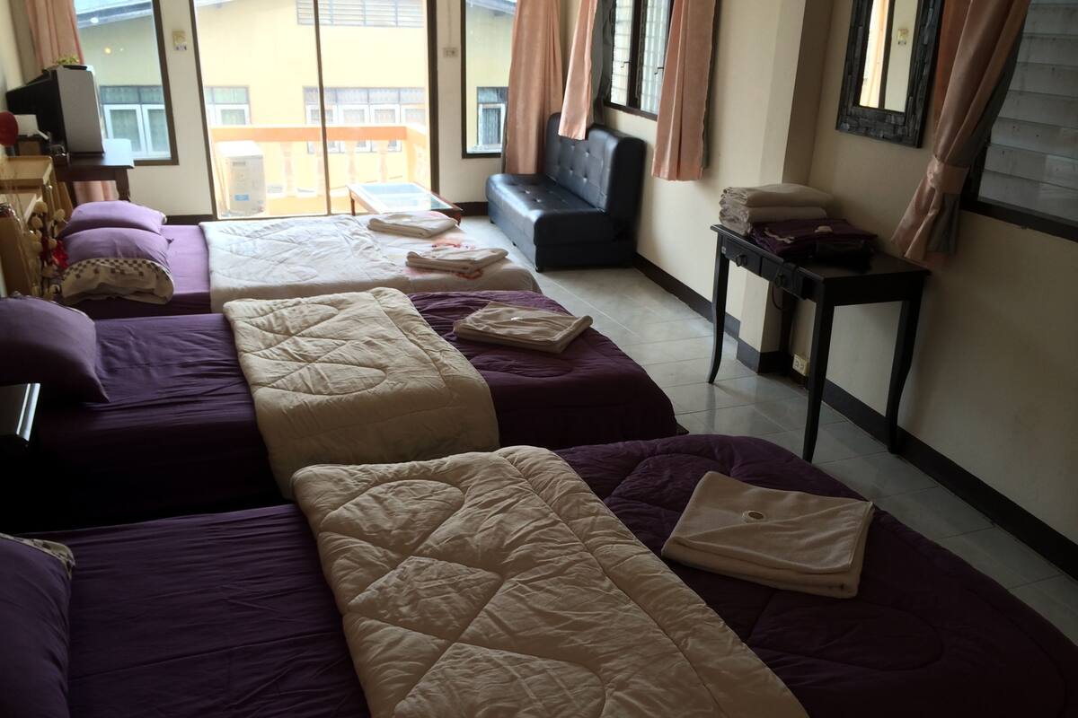 A hotel room with two beds, a sofa, a TV, and a small table.