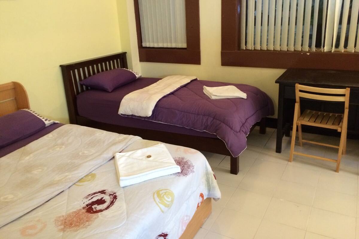 A bedroom with two beds, a desk, and a chair.