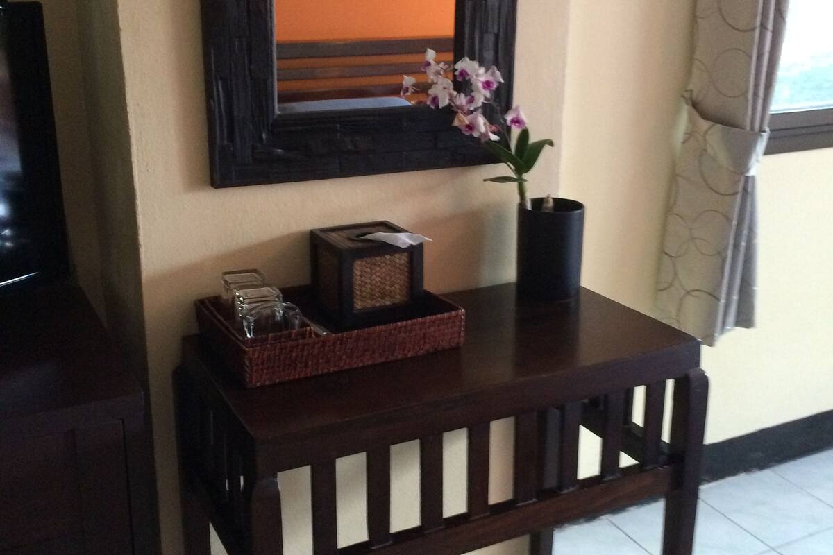 A wooden table with a vase of flowers, a framed picture, and a basket.