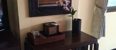A wooden table with a vase of flowers, a framed picture, and a basket.