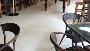 Una sala de billar con mesa de billar, paredes de madera y una zona de bar con taburetes.