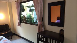 Una habitación con cama, escritorio, espejo y ventana con cortinas.