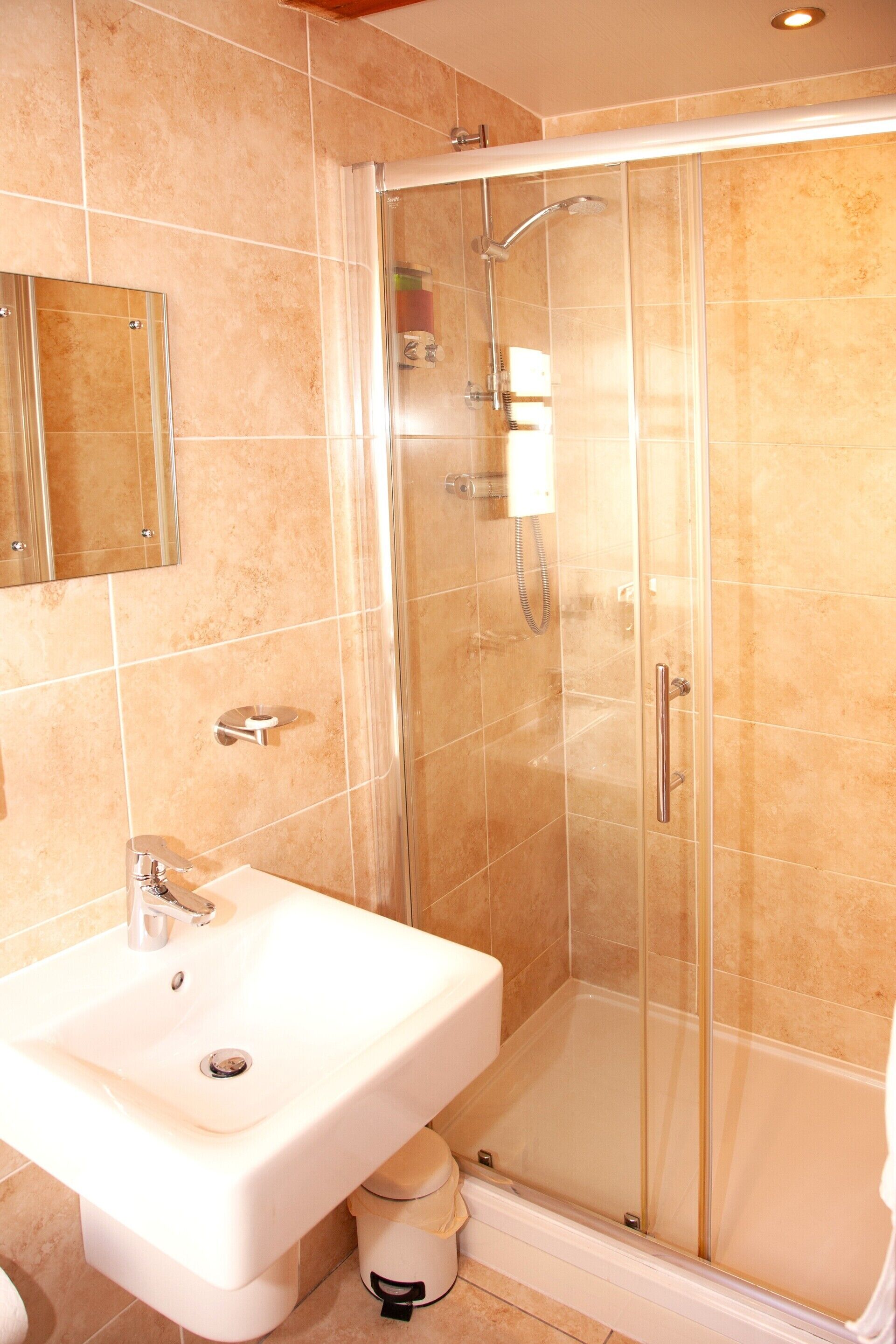 A bathroom with a glass-enclosed shower, a white sink, and a mirror above the sink.